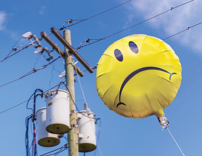 Mylar Balloon with a sad face flying close to power lines 